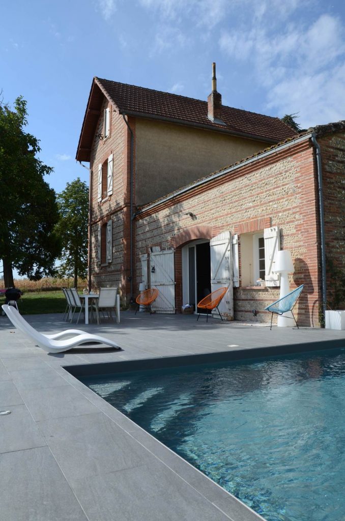 Piscine margelle béton. Chaises Boqa orange et bleu. Toulousaine et ses briquettes.