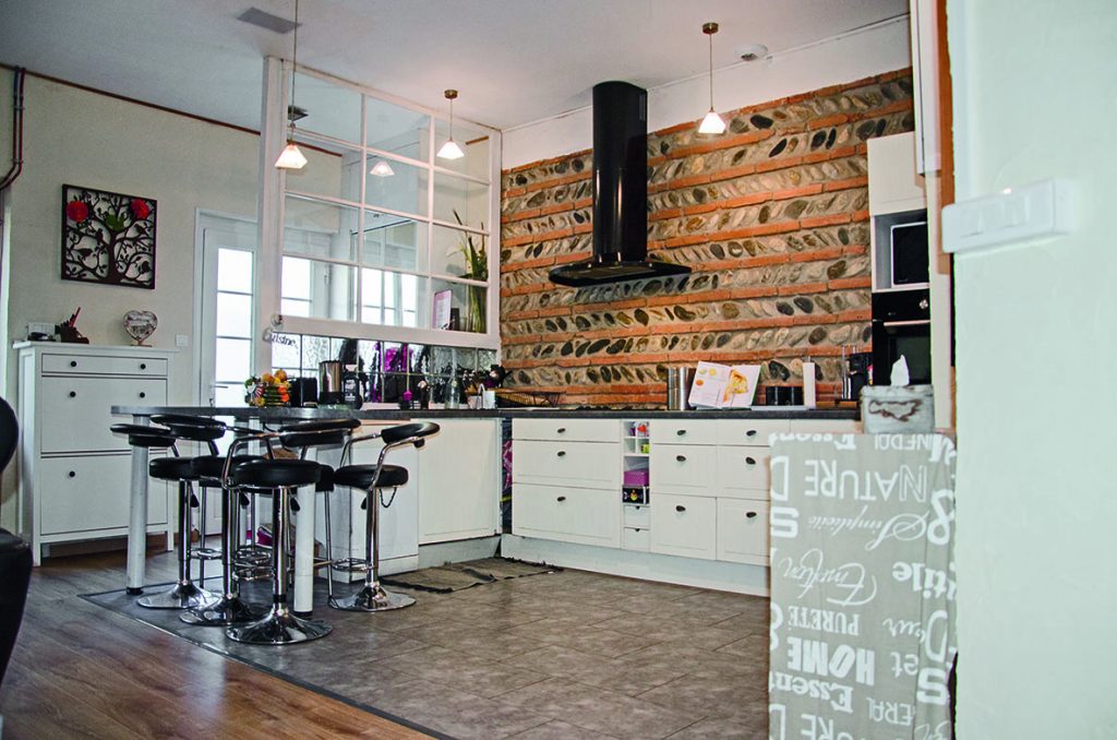 Murs en briquettes foraines et galets dans la cuisine, hotte noire